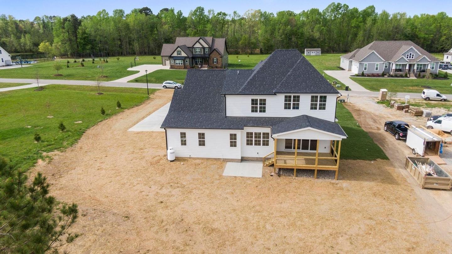 Aerial view of a newly built home on a cleared lot in a growing subdivision