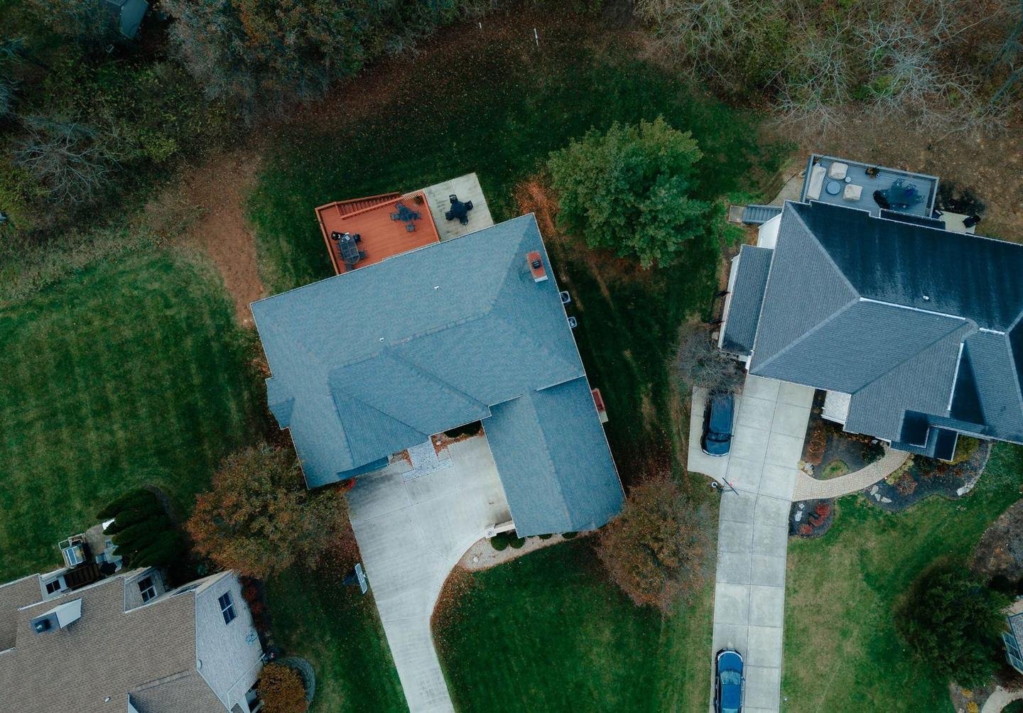 Top-down aerial view of suburban homes, driveways and lawns