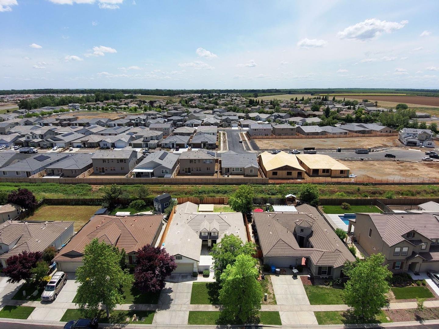 Aerial view of an established neighborhood beside a new subdivision under construction and open farmland